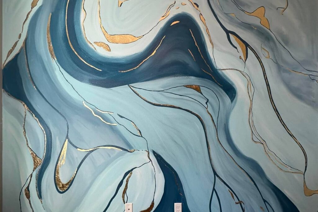 Abstract wall mural featuring swirling blue and teal waves accented with gold and black lines, creating a fluid, marble-like pattern. Two white electrical outlets are visible at the bottom of the image.